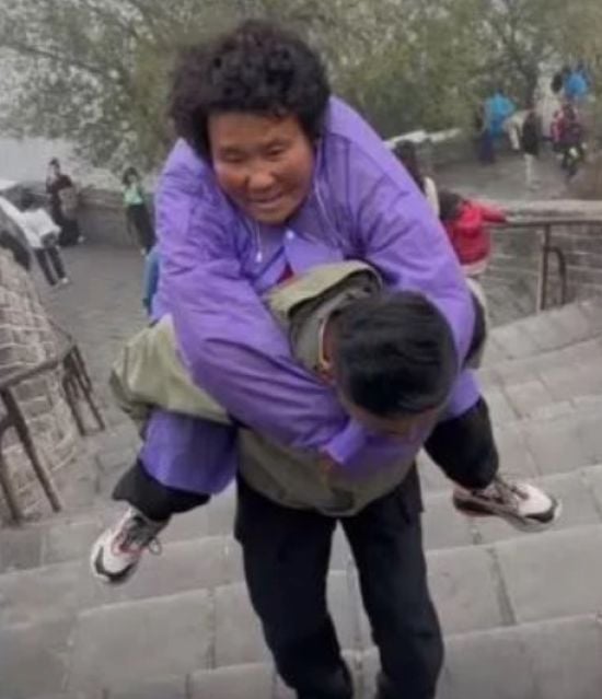 Син продав своє майно та подорожує з паралізованою матір'ю, несучи її на спині – фото, відео